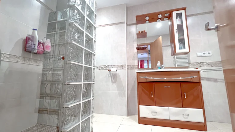 Bathroom with walk-in glass block shower and wooden vanity in Maryvilla Calpe