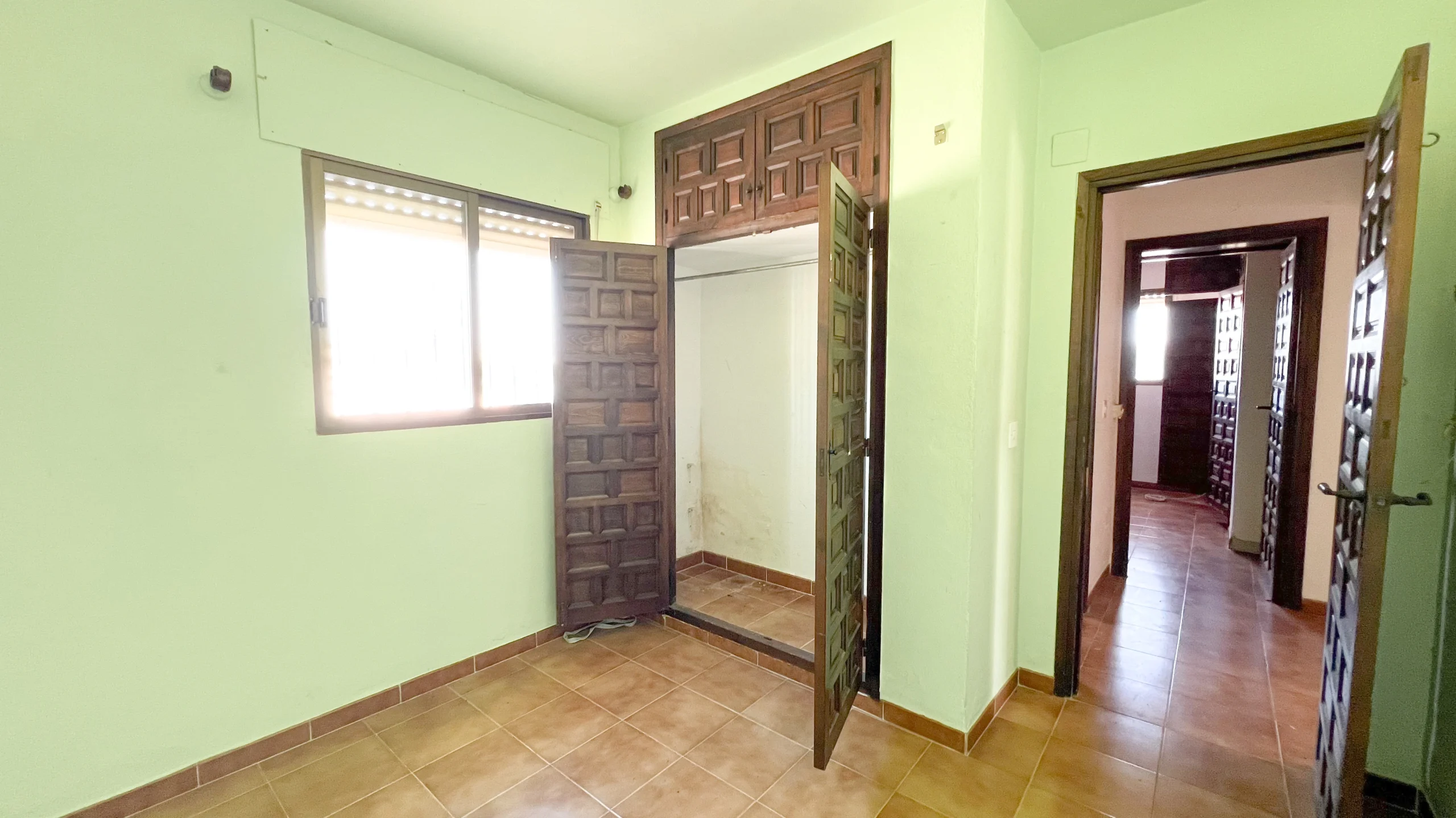 Bedroom with green walls and wooden wardrobe in Calpe house to renovate