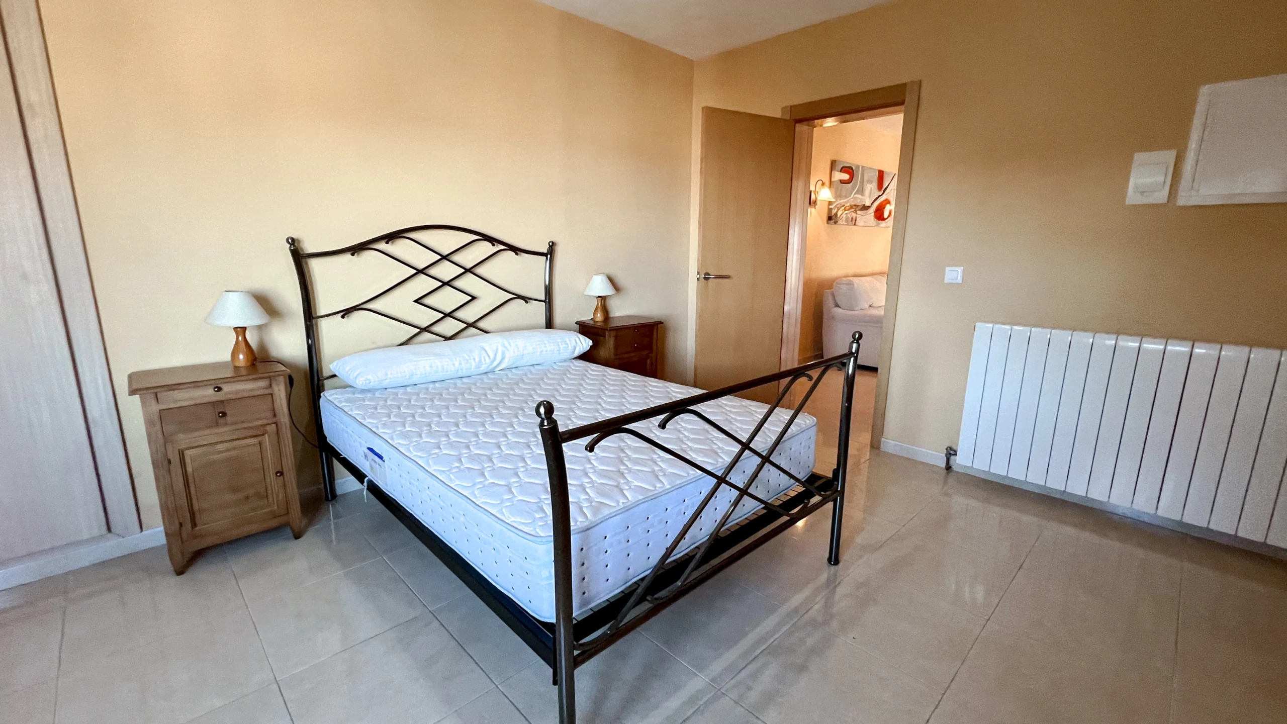 Bedroom with iron bed frame and en-suite access in Maryvilla Calpe property