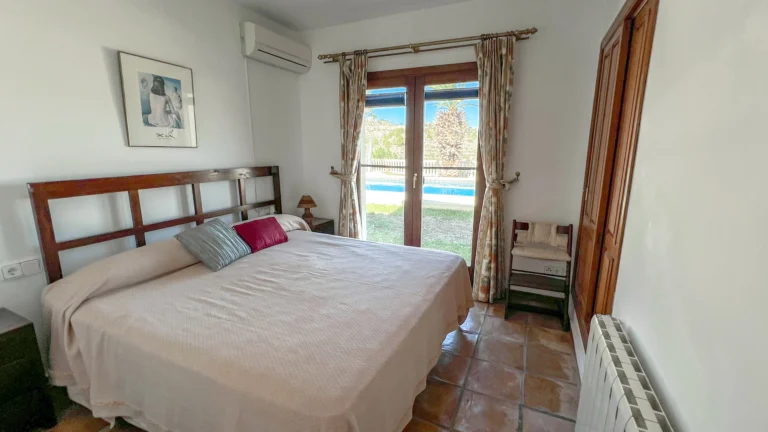 Bedroom with wooden headboard and terrace access in Benissa countryside home