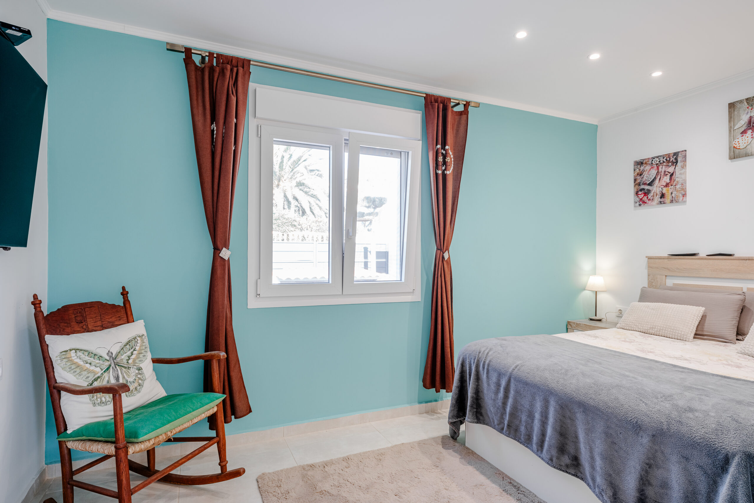 Bright double bedroom with turquoise accent wall and window views in a Calpe villa