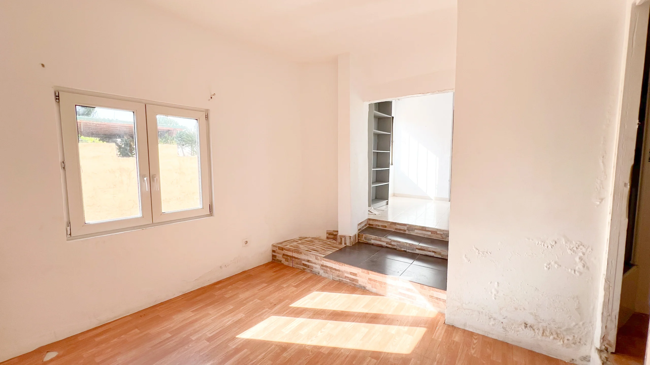 Bright room with step entrance and wooden flooring in a home to renovate