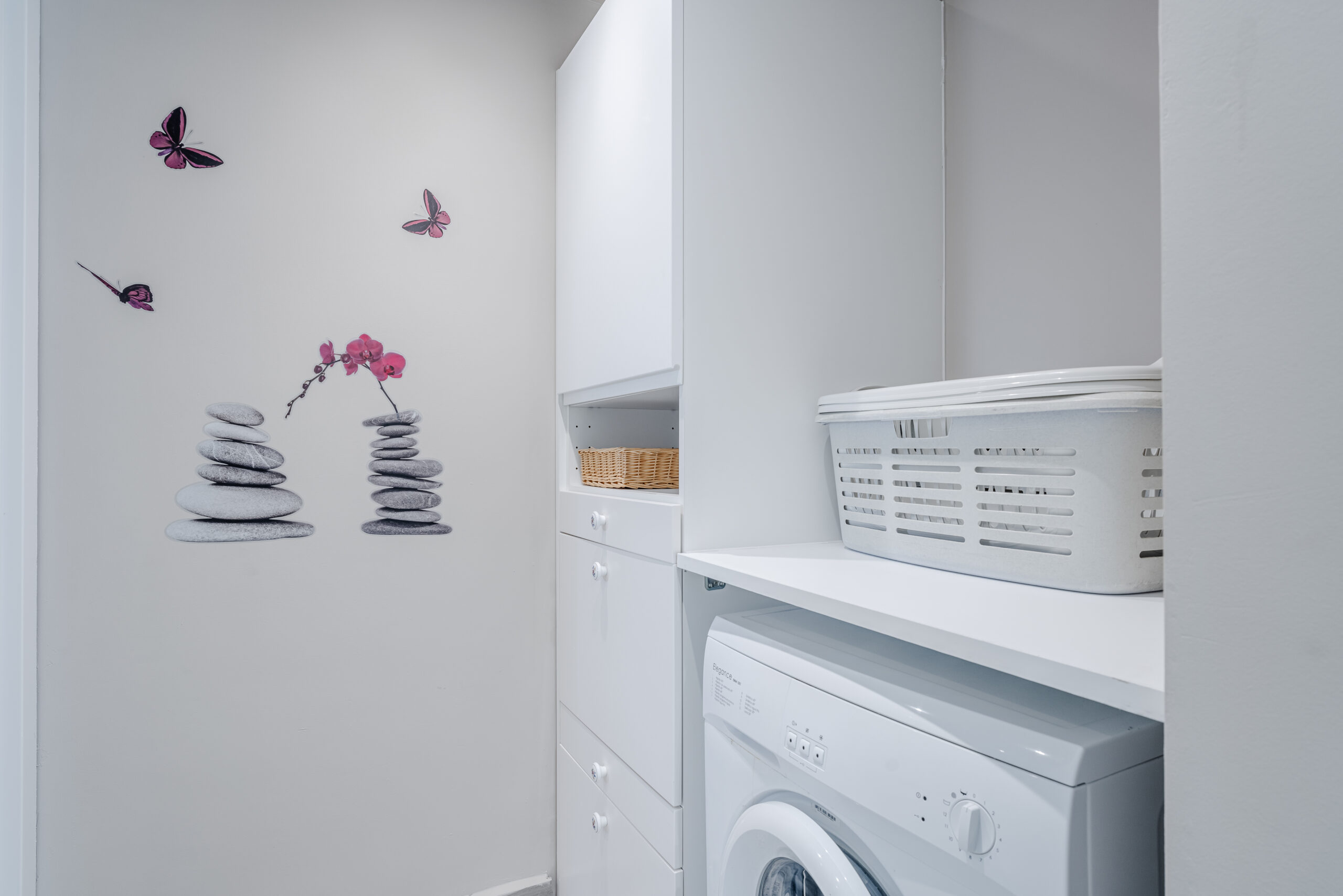 Compact laundry station inside guest apartment with storage cabinets in a Calpe villa