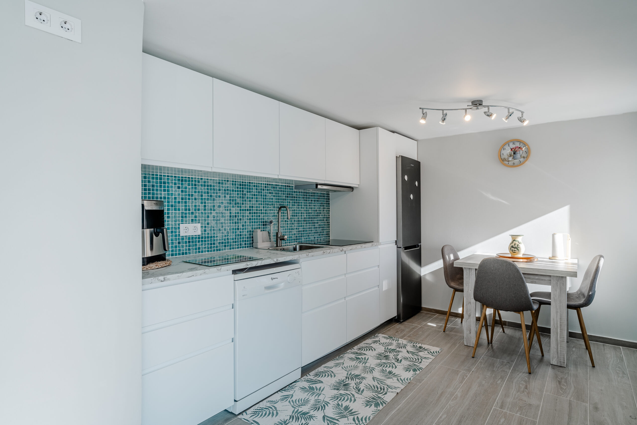 Contemporary white kitchen with mosaic backsplash and dining area in a guest suite in Calpe
