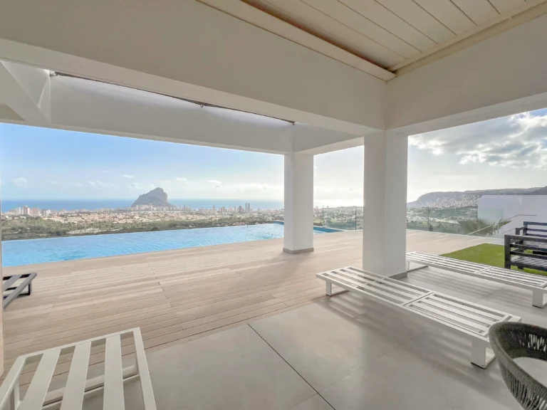 Covered terrace lounge with infinity pool and sea views in a luxury villa in Calpe