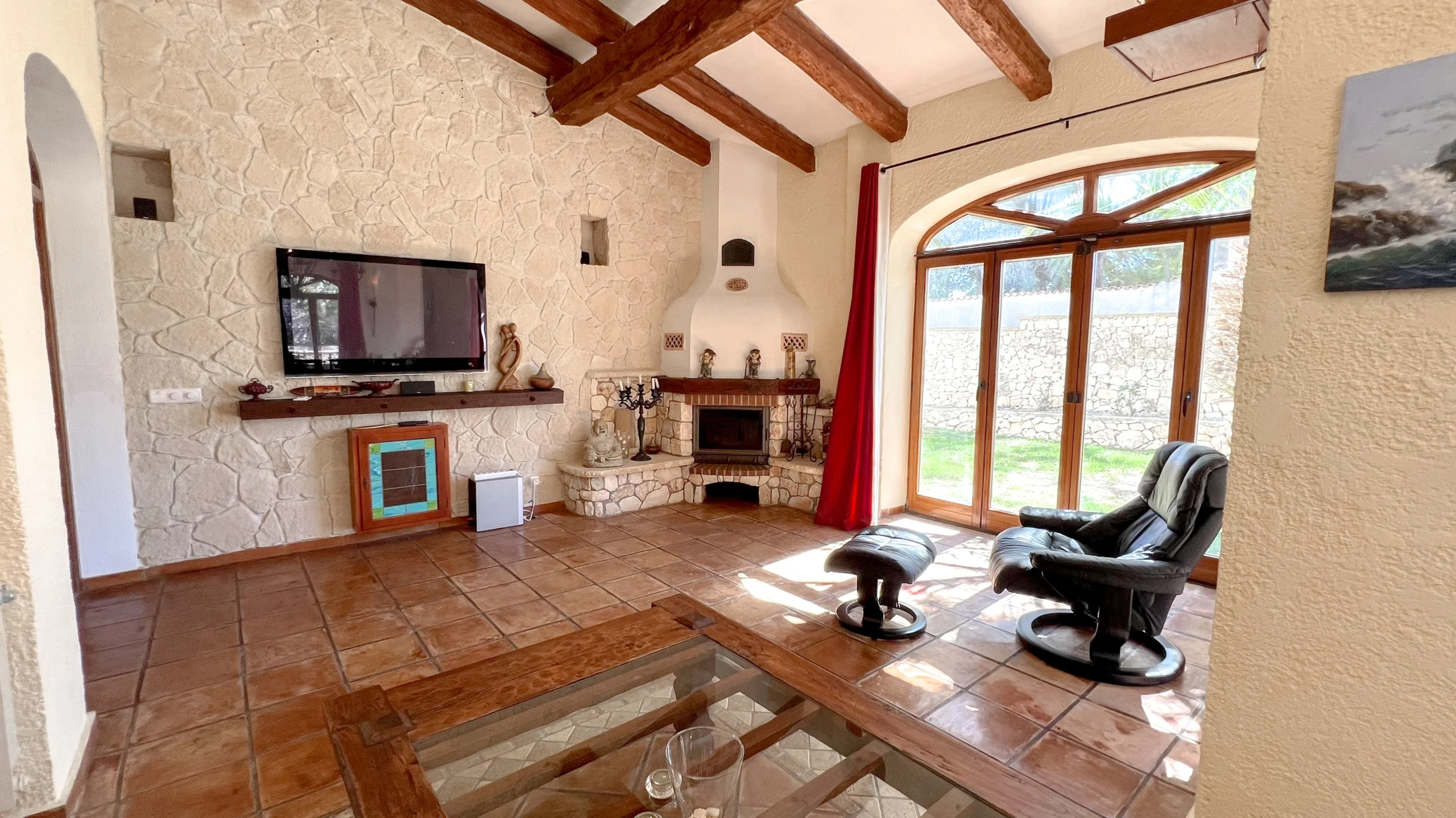 Cozy living room with stone walls, fireplace, and wooden beams in Benissa finca