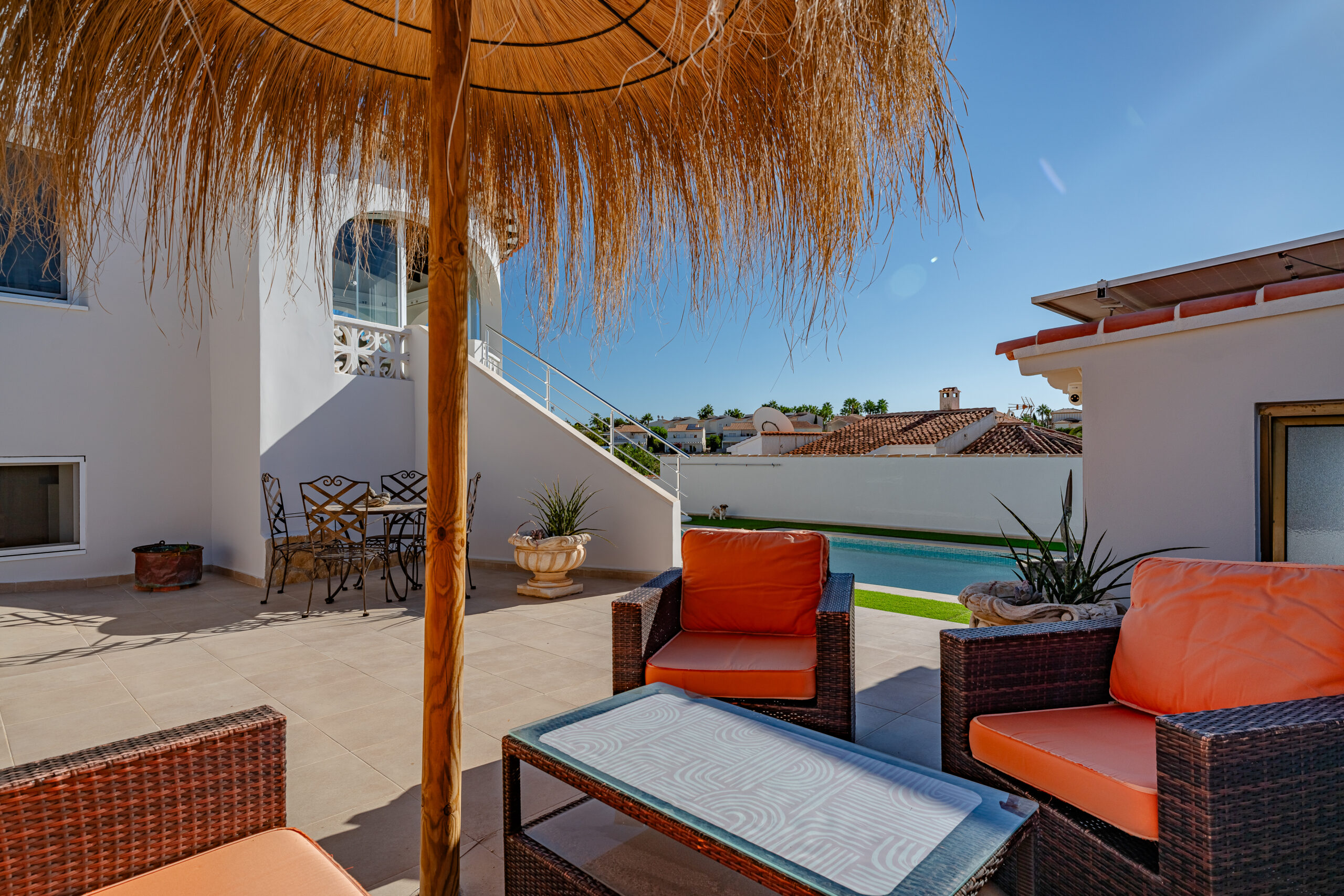 Cozy rattan lounge area with orange cushions beside the pool in a Mediterranean villa