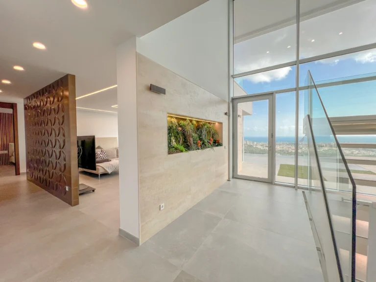 Entrance hallway with glass staircase and sea-view window in a luxury villa in Calpe