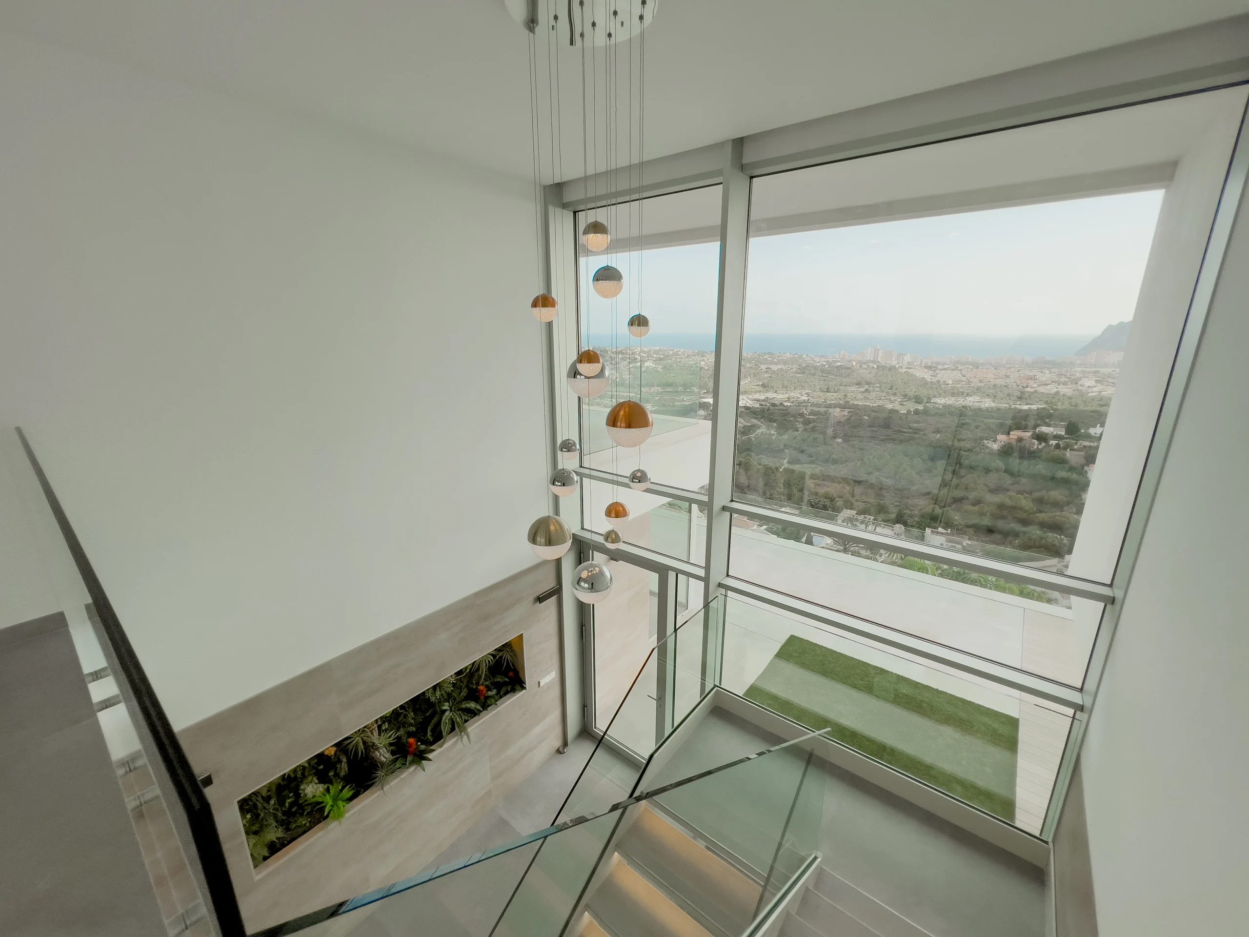 Glass staircase landing with hanging lights and panoramic sea views in Calpe