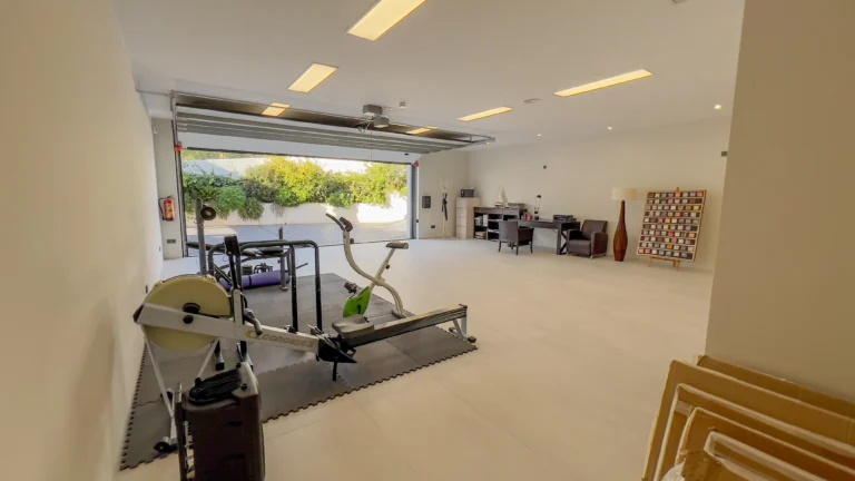 Home gym with open garage door in modern seafront villa Altea