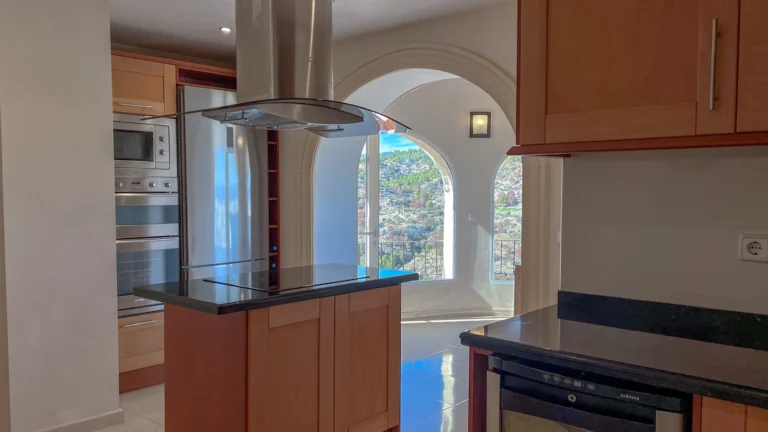 Kitchen island with extractor hood and arched window views in Maryvilla villa