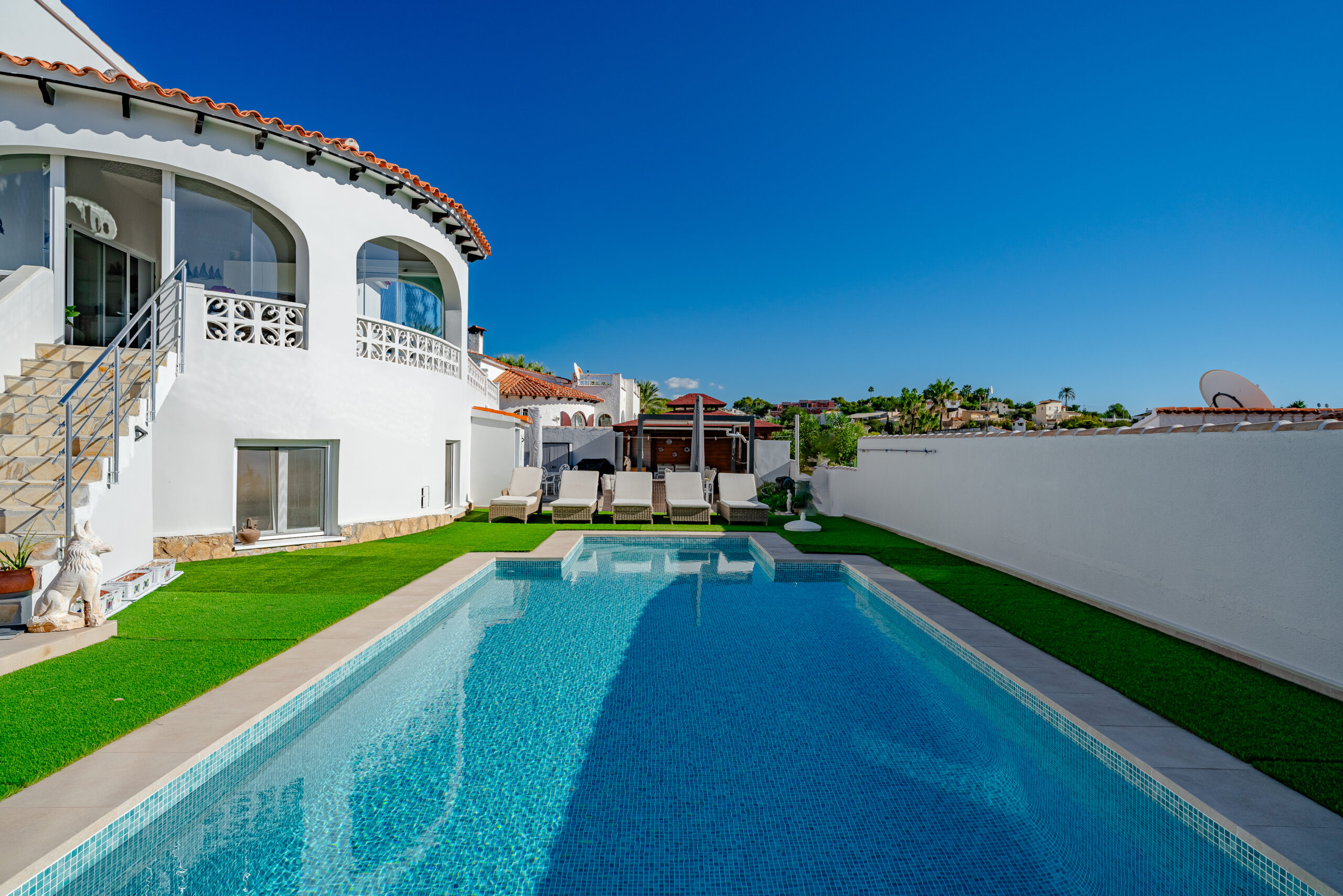 Large rectangular pool with artificial grass sunbathing area in a renovated Calpe villa