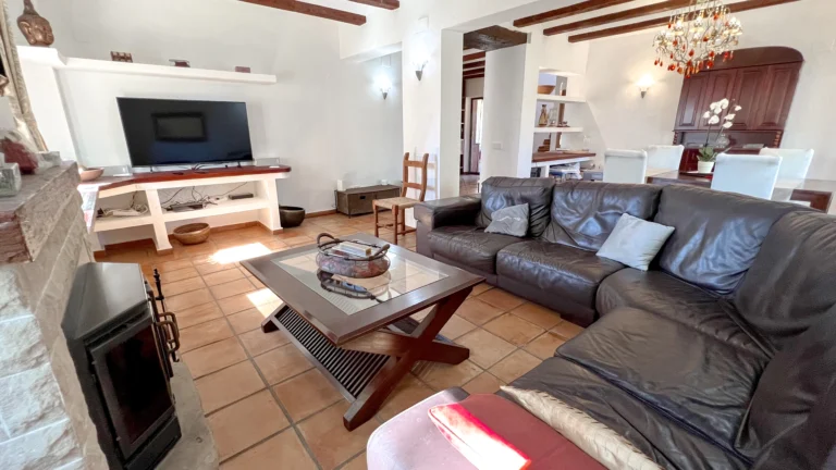 Living room with fireplace, dark leather sofa, and beamed ceilings in rustic Benissa home