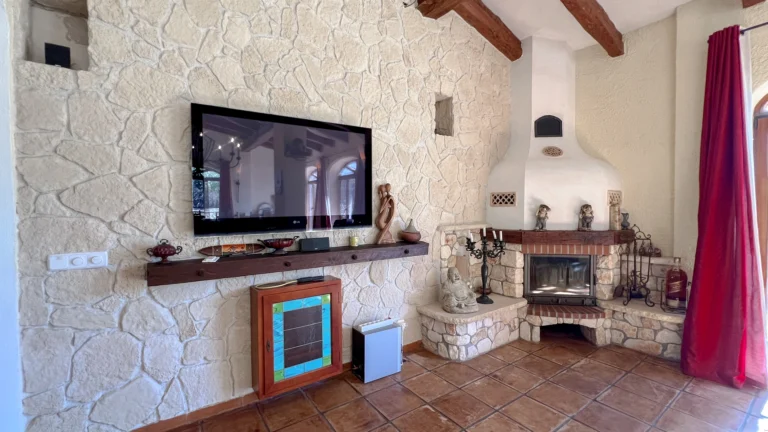 Living room with stone fireplace and TV in rustic Benissa home