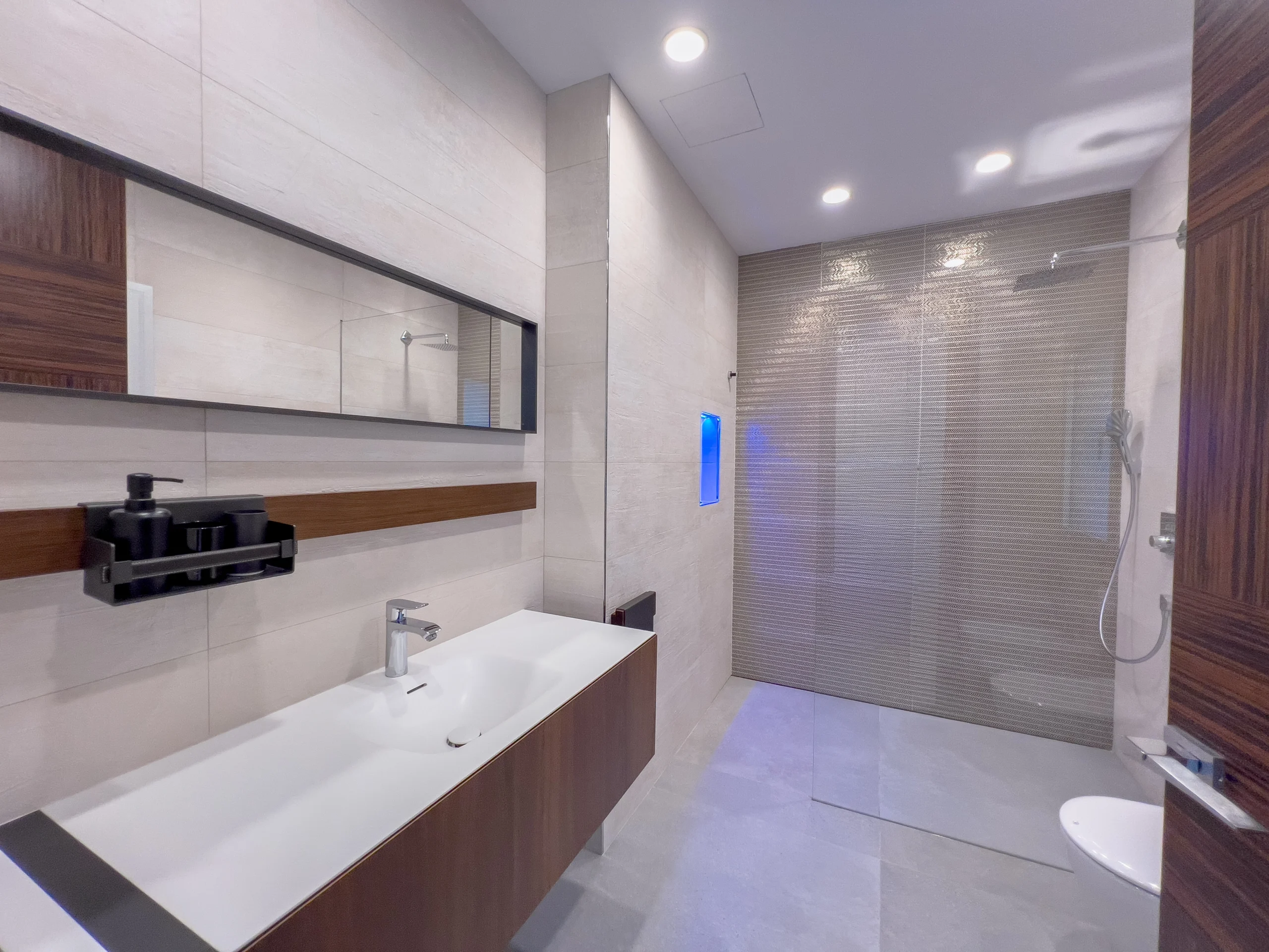 Luxury bathroom with floating vanity, mirror lighting, and walk-in rain shower in a modern villa