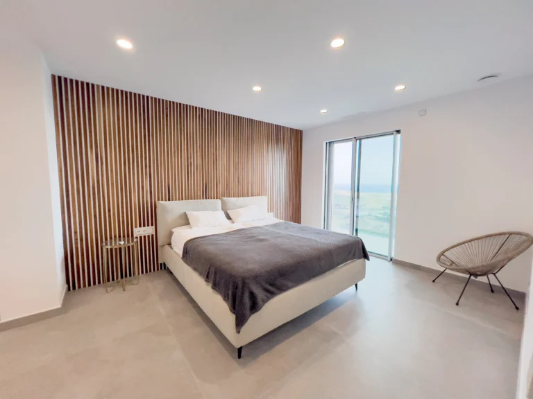 Master bedroom with wooden accent wall and terrace access overlooking Calpe