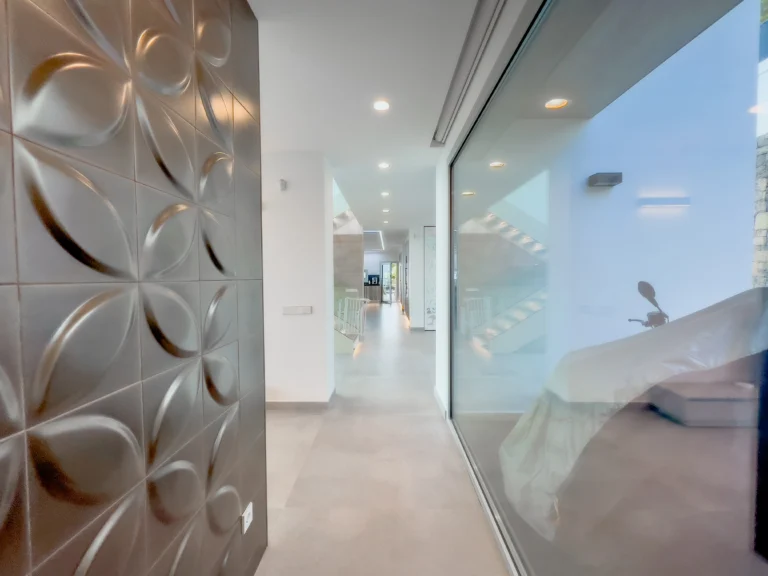 Modern corridor with textured feature wall and large glass window in a luxury villa