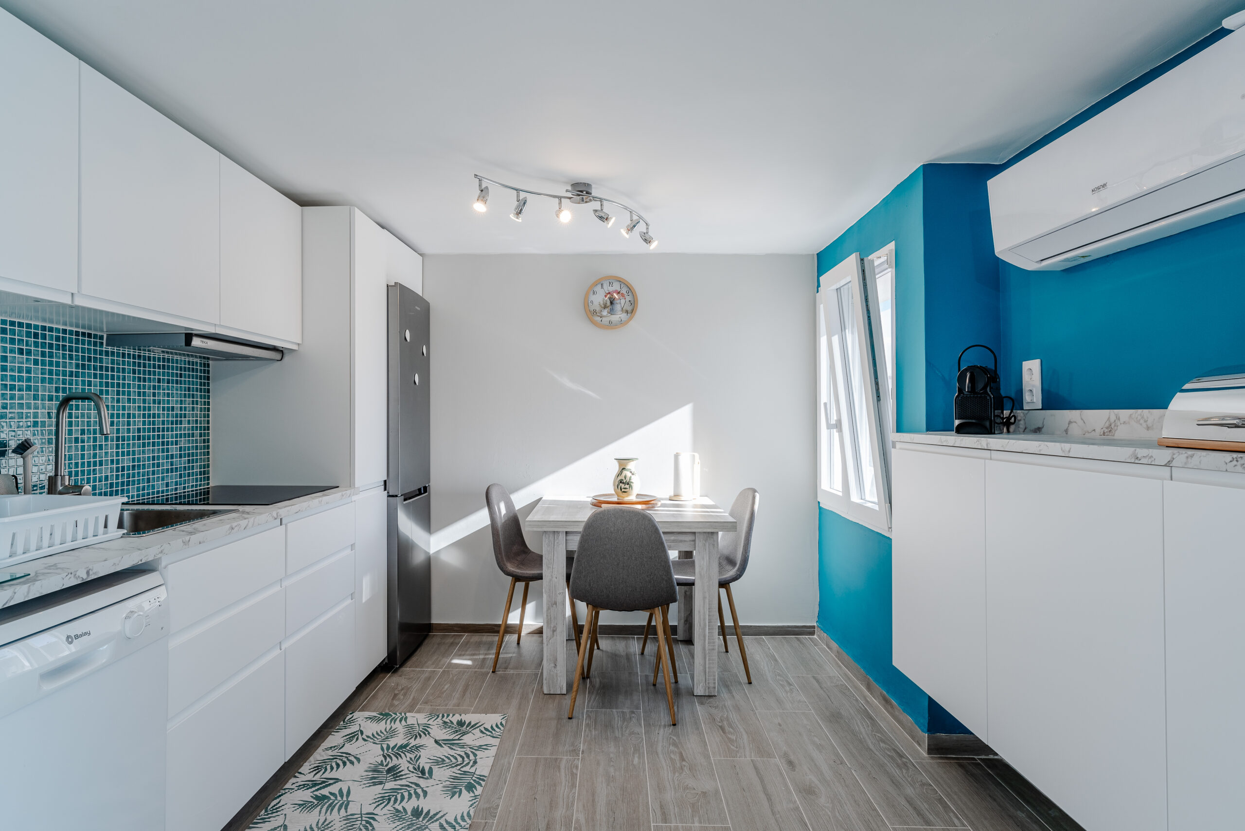 Modern guest apartment kitchen with turquoise wall and dining table in a Calpe villa