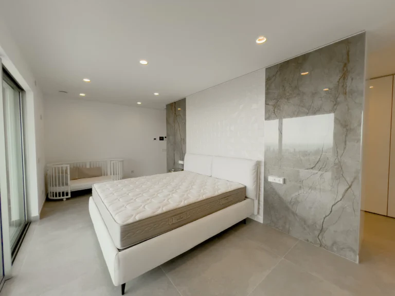 Modern master bedroom with marble accent wall and terrace access