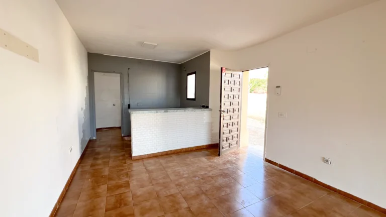 Open-plan living area with tiled floors and front door access in Calpe