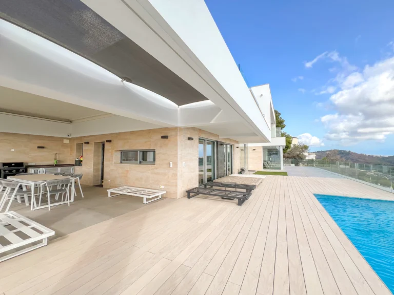 Outdoor dining and sunbathing deck with infinity pool in modern Calpe villa