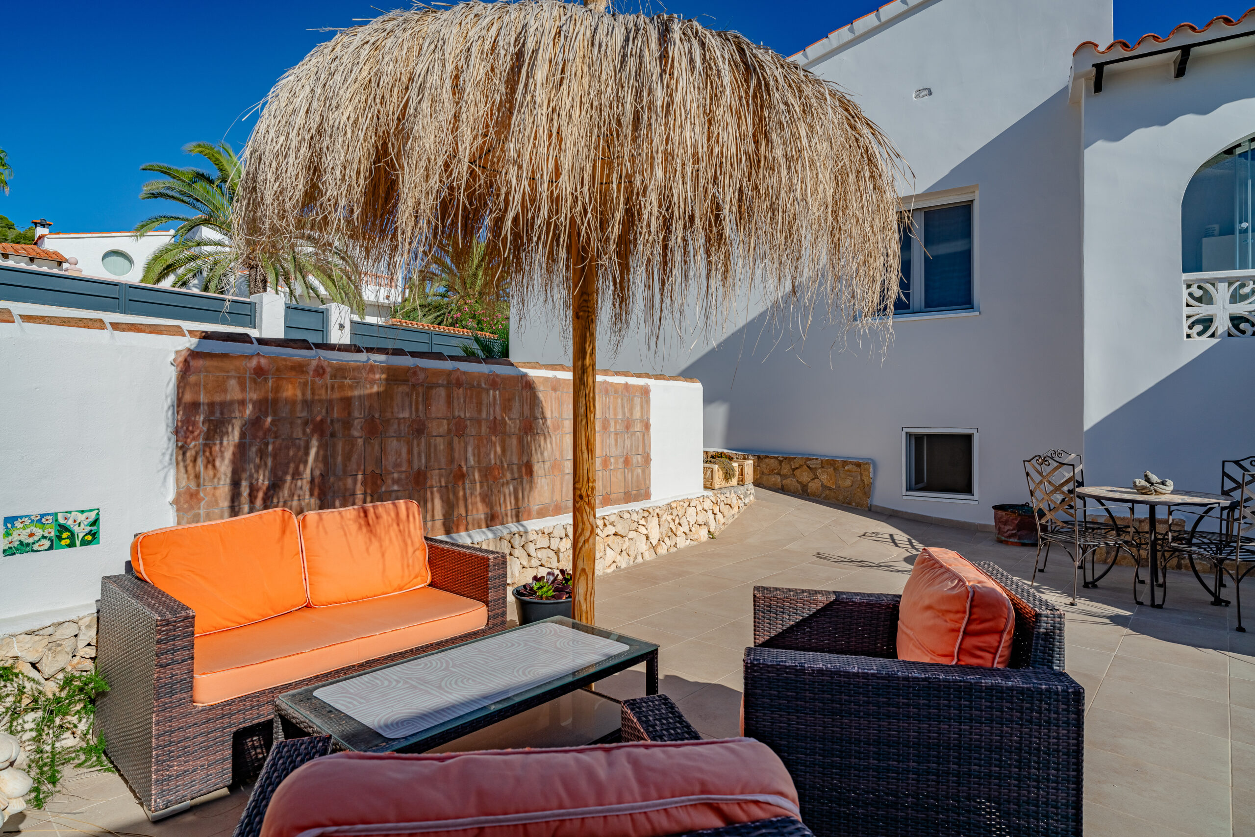 Outdoor seating area with thatched umbrella in a Mediterranean villa