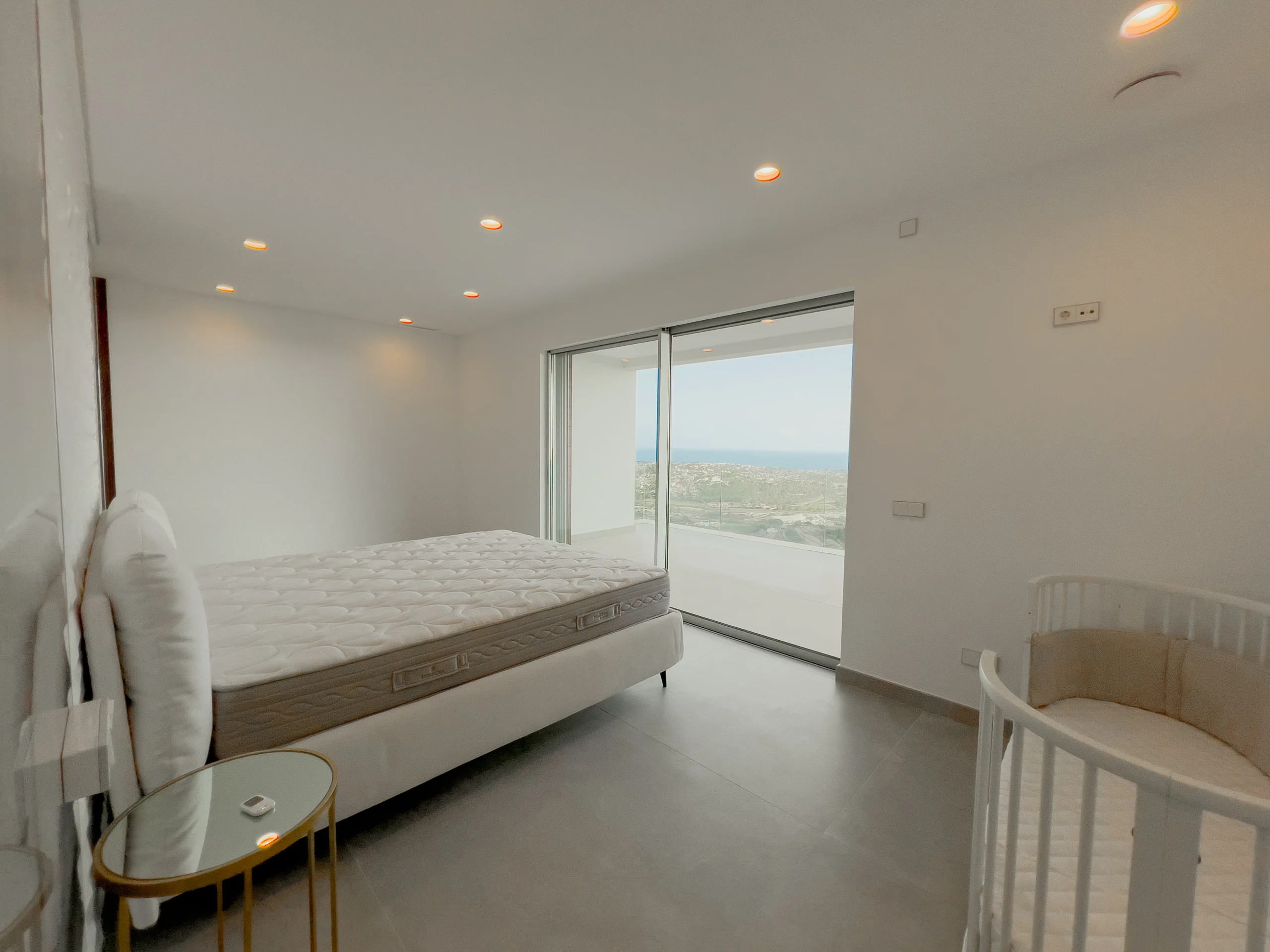 Sea-view ensuite bedroom with sliding glass doors and minimalist decor