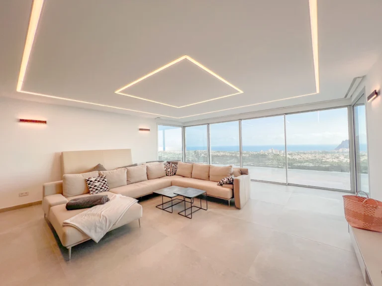 Spacious living room with LED ceiling lighting and full glass windows overlooking Calpe