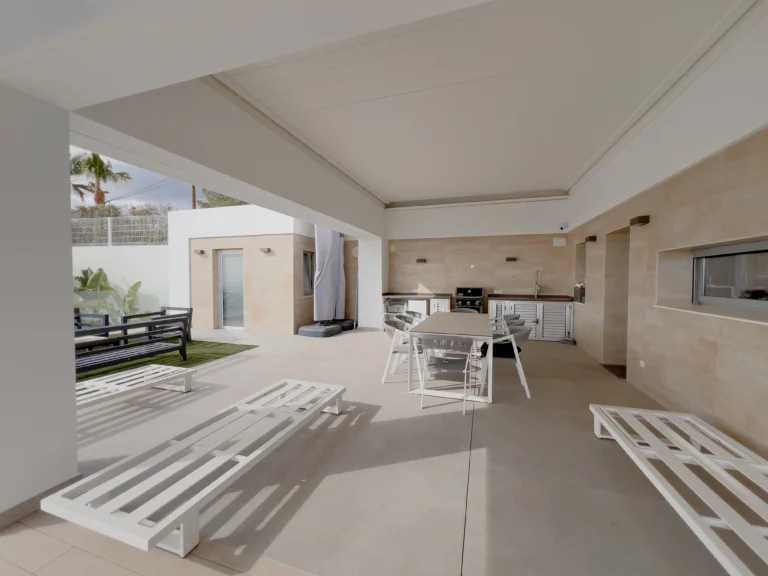 Spacious shaded terrace with loungers and outdoor kitchen in a luxury villa