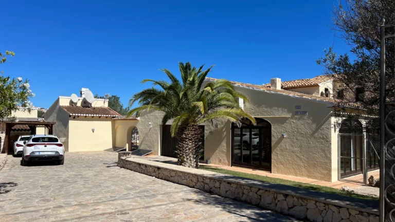 Stone driveway entrance with palm trees and garage at Benissa finca