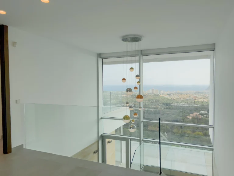 Upper hallway with full-height windows and pendant lighting overlooking Calpe