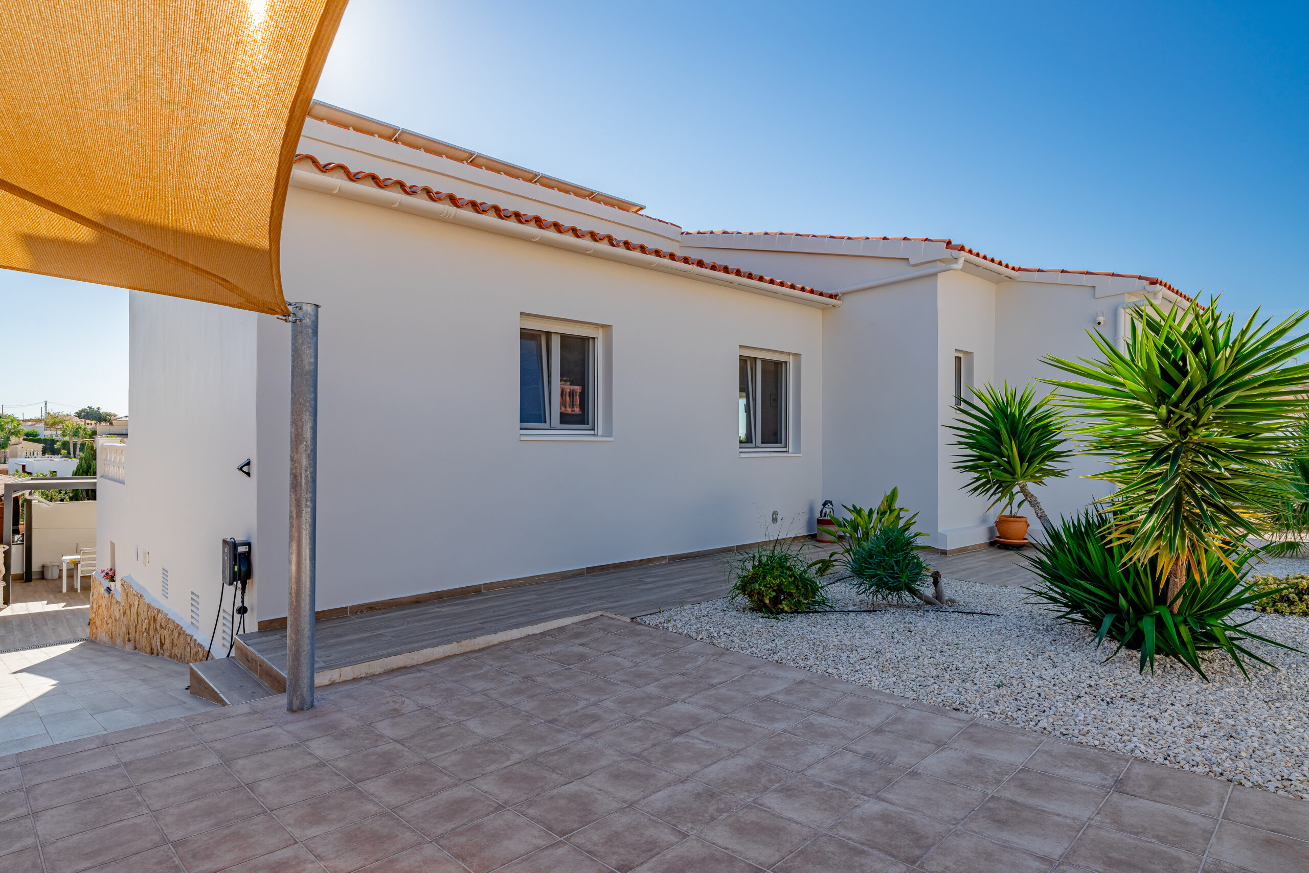 Villa entrance with landscaped garden and shade sail in a modern Calpe property