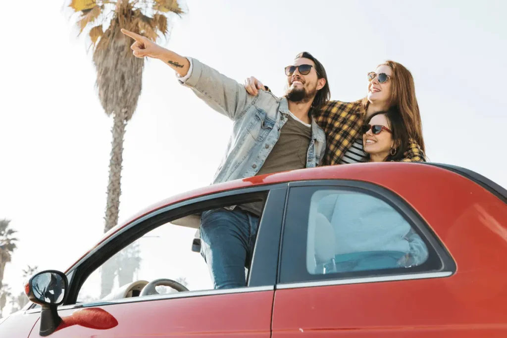Group of friends in a convertible car pointing to a water park near Calpe, illustrating a fun family day trip activity on the Costa Blanca.