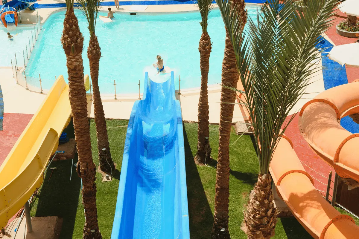 Panoramic view of the main blue water slide surrounded by palm trees at a top water park near Calpe, highlighting excellent family leisure and holiday amenities in the area.