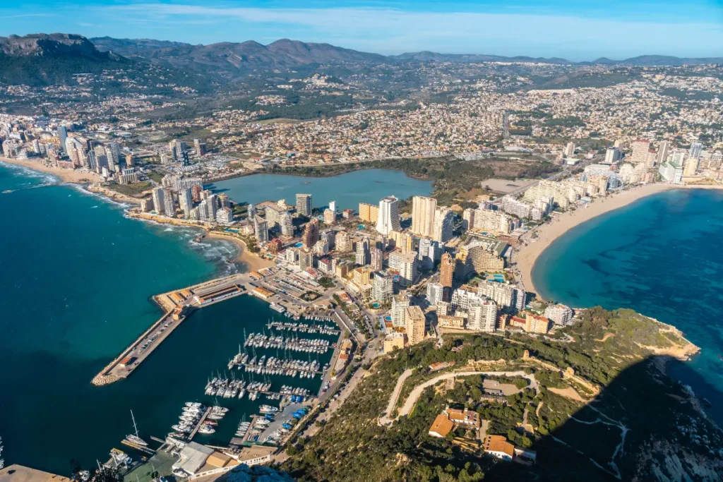 Aerial view of Calpe from the Peñón de Ifach, showing La Fossa, Arenal-Bol, the marina, beaches, apartment areas and surrounding residential zones.
