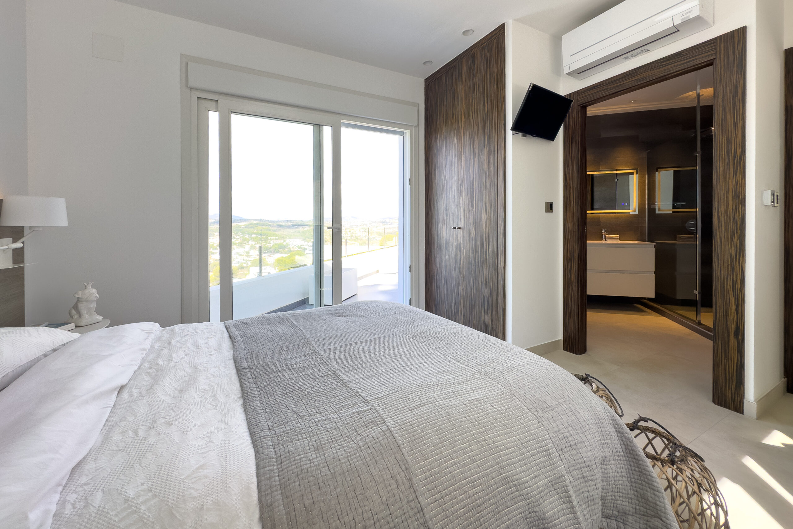 Bedroom with balcony doors and ensuite access in a Moraira villa