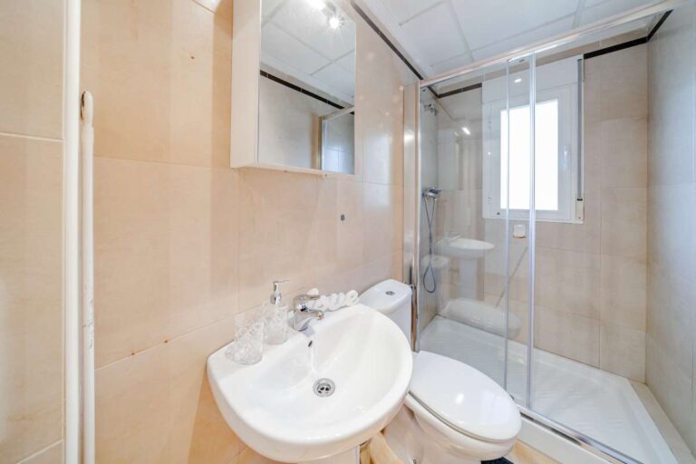 Bathroom inside a semi-detached house in Calpe with shower enclosure, sink, toilet and natural light