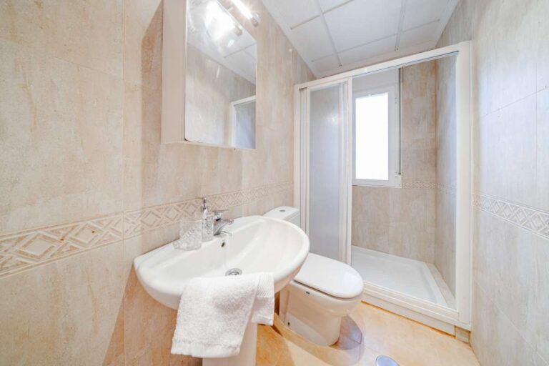 Bathroom inside a semi-detached house in Calpe with shower enclosure, sink, toilet and natural light
