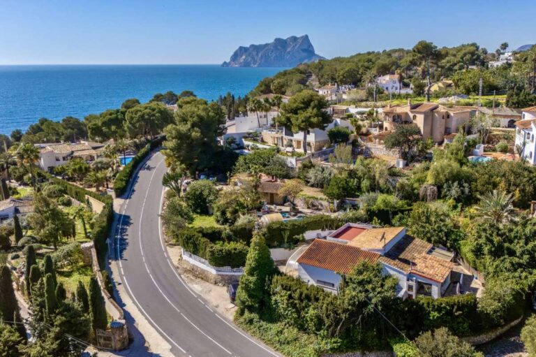 Aerial coastal view near Cala Baladrar in Benissa Costa showing the Mediterranean Sea, surrounding villas and road access