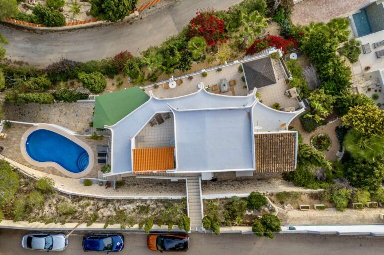 Aerial view of a Benissa villa with private swimming pool, terraces, parking area and Mediterranean garden surroundings