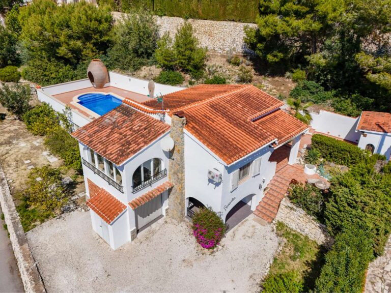Aerial view of a charming Benissa Coast villa with private pool, red-tiled roof, garage area, surrounding garden and Mediterranean setting