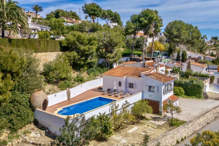 Aerial view of a charming Benissa Coast villa with private swimming pool, red-tiled roof, garden areas and sea views