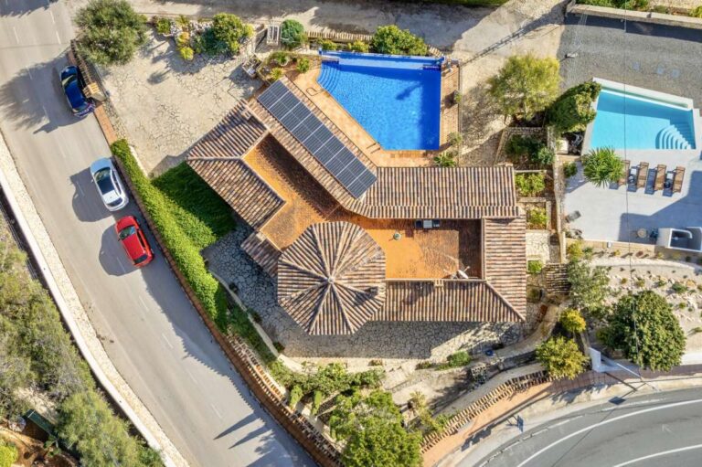 Aerial view of a finca-style villa in Benissa Costa with private pool, solar panels, tiled roof, driveway and surrounding residential setting