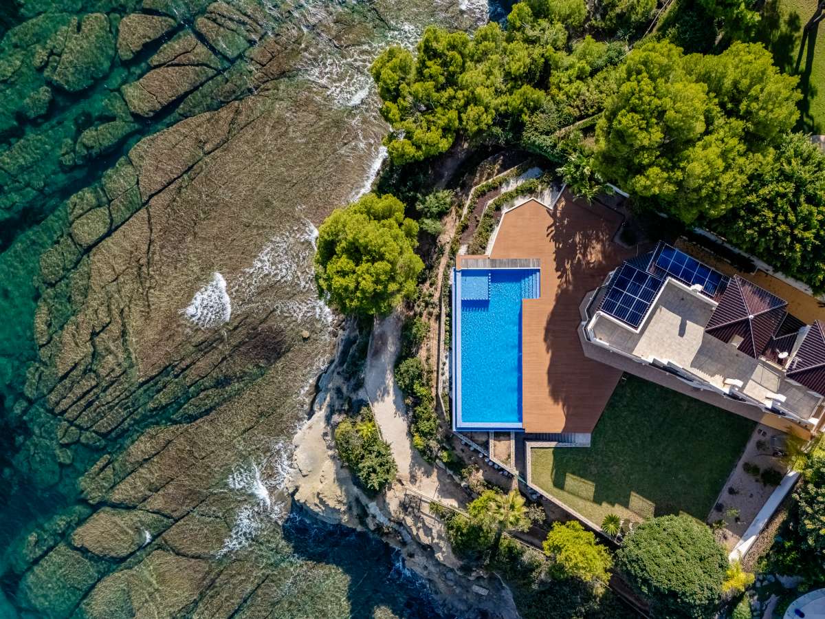 Aerial view of a frontline villa plot with private pool and direct coastal position in Les Bassetes.
