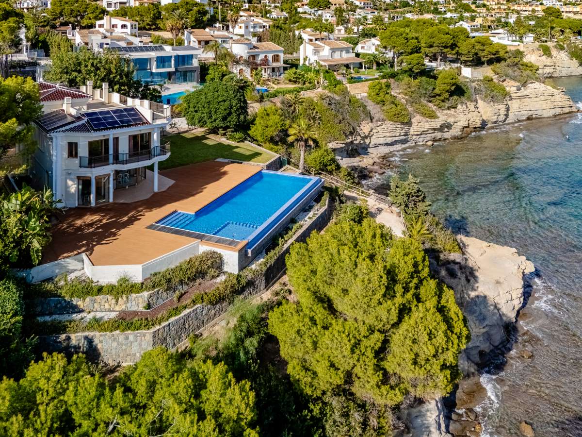 Aerial view of a frontline villa with private pool beside the rocky coastline in Les Bassetes, Benissa Coast.