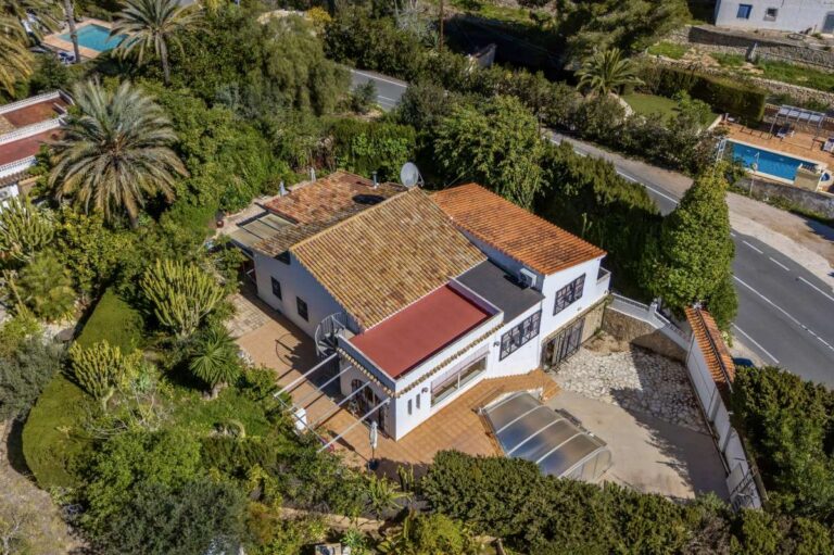 Aerial view of a Mediterranean villa near Cala Baladrar in Benissa Costa with covered pool, garden areas and roadside location