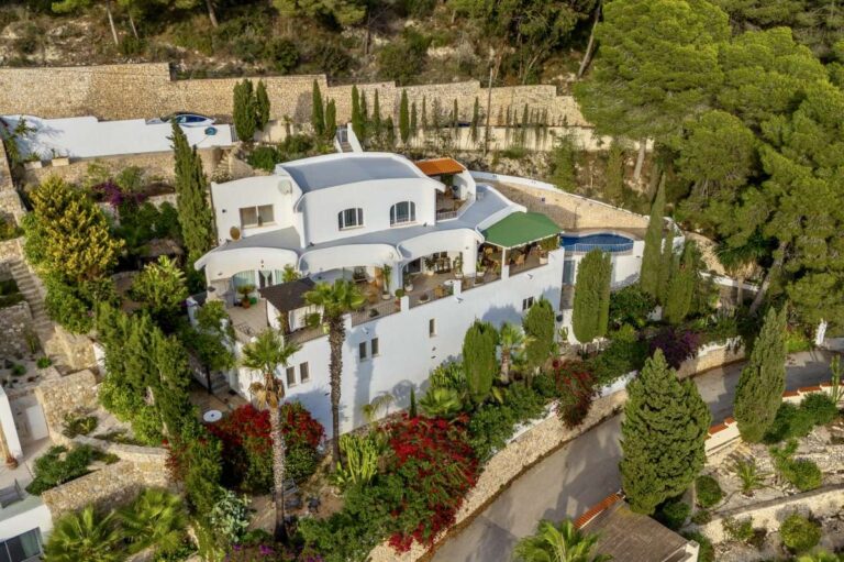 Aerial view of a panoramic sea view villa in Benissa with private pool, landscaped gardens, terraces and hillside setting