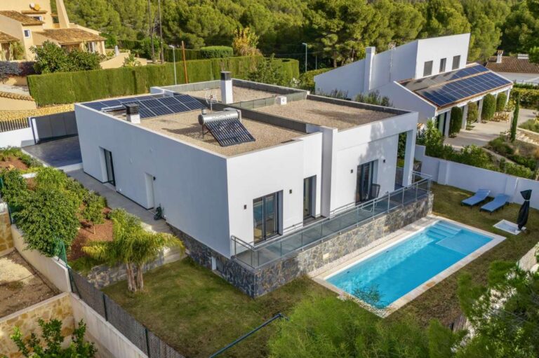 Aerial view of a single-level modern villa in Santa Clara, Altea with saltwater pool, solar panels, white exterior, lawn and private garden