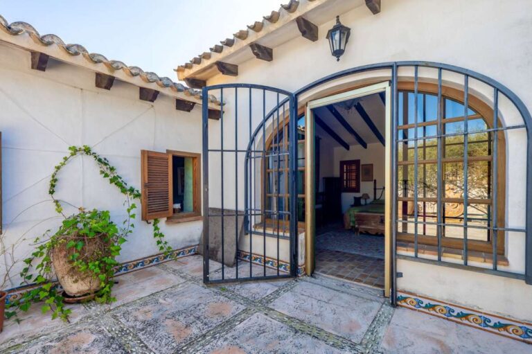 Arched entrance to the guest house at a traditional Spanish finca near Moraira with metal gates, wooden shutters and rustic exterior details