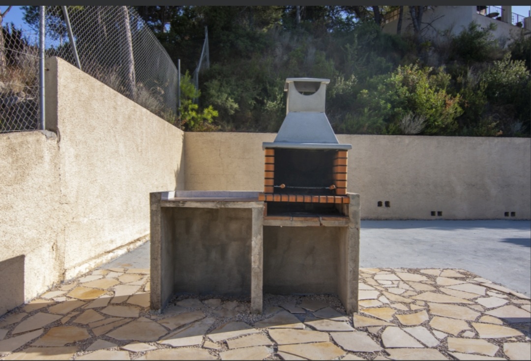Barbecue area with stone terrace beside the garden at a Mediterranean villa in Calpe.